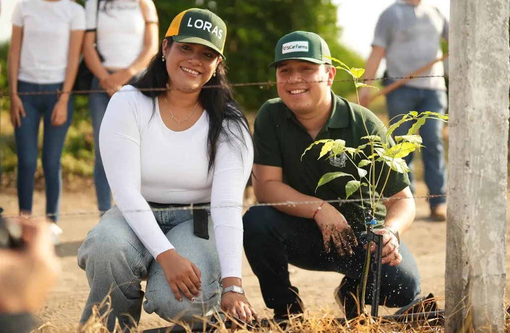 Dos participantes junto a un árbol nativo recién plantado