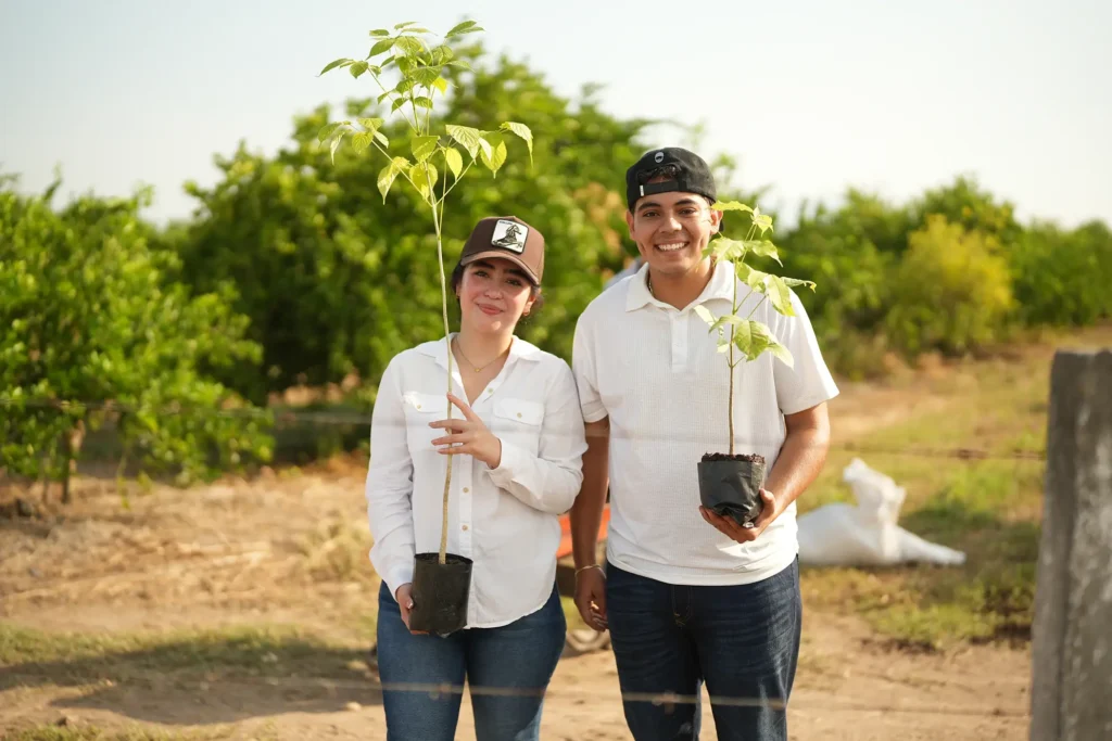 Dos participantes sostienen ejemplares de especies nativas listos para plantar
