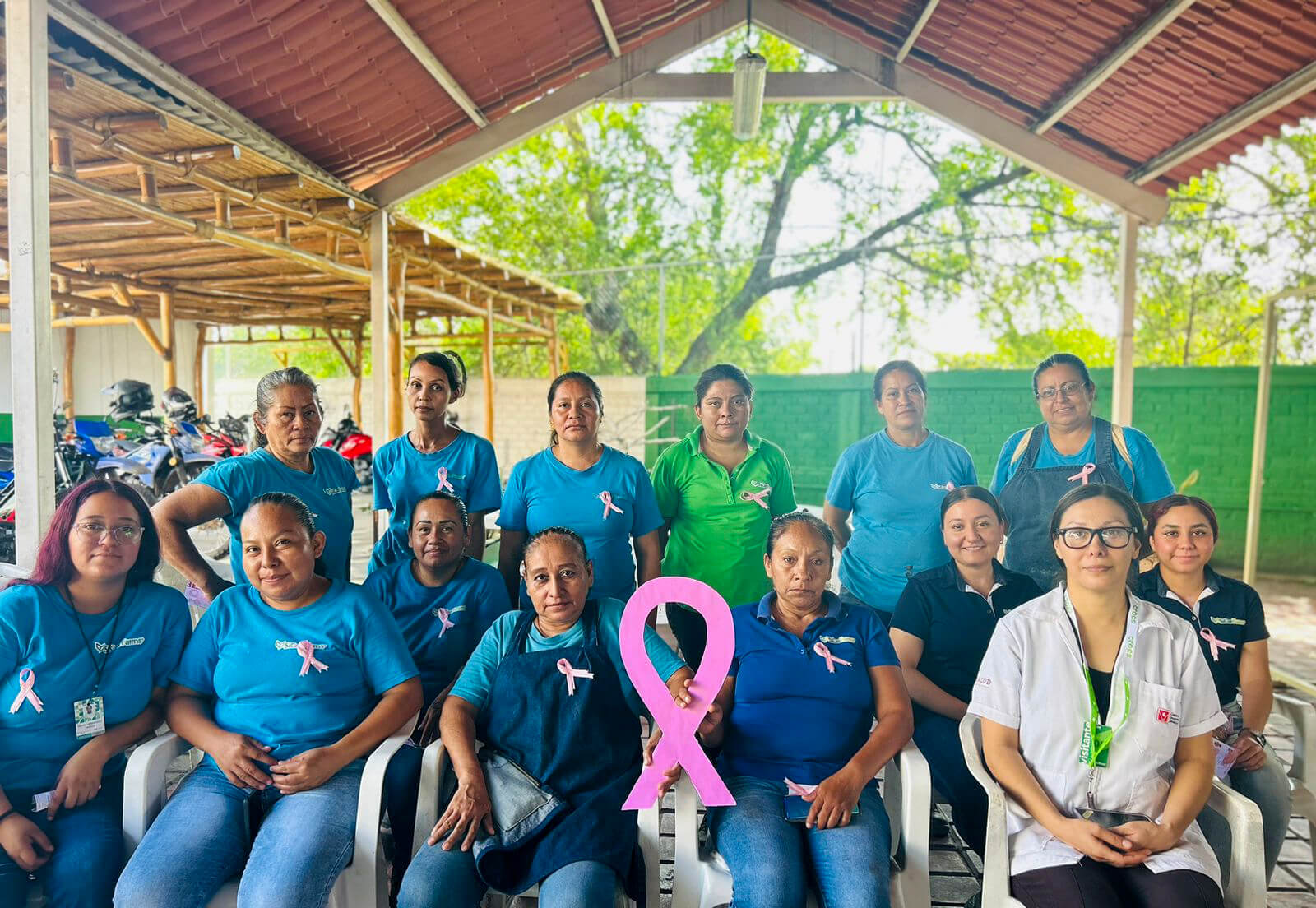 Colaboradoras con listones rosas reunidas durante la campaña contra el cáncer de mama