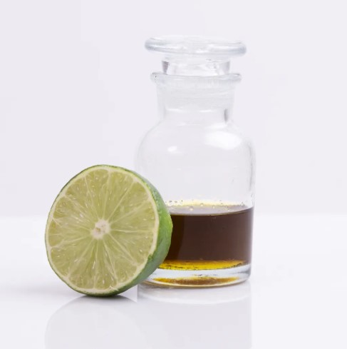 Frasco de aceite esencial de limón junto a medio limón